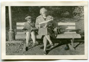 Woman and girl sitting on a bench reading.